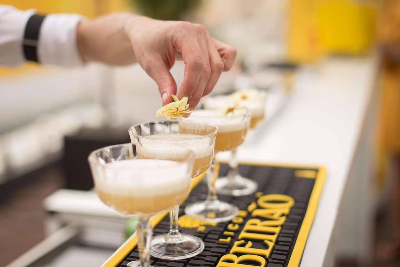 A bartender adding a yellow flower to a cocktail.